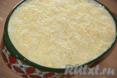 На мелкой тёрке натереть сыр и выложить пышной шапкой поверх салата.