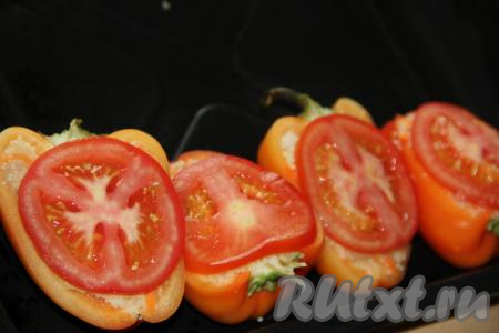 Выложить подготовленные половинки перцев с начинкой из фарша с кускусом на противень. Помидор вымыть и нарезать на кружочки. На каждую половинку перца положить по одному кружочку помидора.
