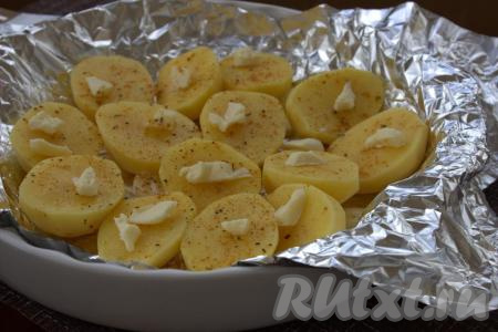 Затем картофель посолить, приправить специями по вкусу. Положить на каждую половинку картошины по небольшому кусочку сливочного масла.