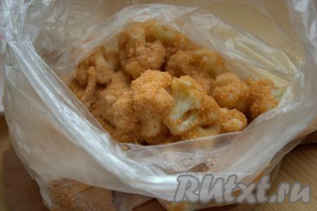 Панировочные сухари посолить и приправить по вкусу. Всыпать сухари в полиэтиленовый пакет, туда же выложить кусочки цветной капусты в яичной смеси. Плотно закрыть пакет и хорошо перемешать цветную капусту с панировочными сухарями (чтобы сухари равномерно покрыли соцветия капусты).