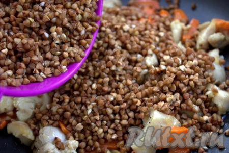 Когда морковь станет мягкой, добавить гречку в сковороду к куриному филе и овощам, разровнять.