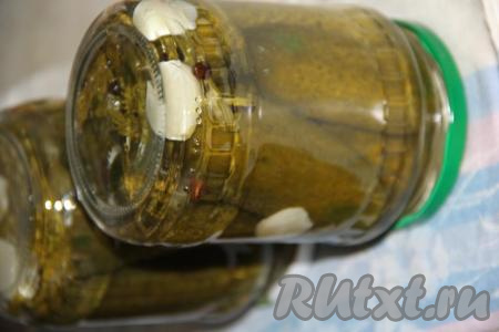 Аккуратно достать банки из горячей воды, закрутить крышки. Перевернуть баночки с огурчиками вверх дном, укутать в одеяло и оставить до полного остывания. После того как банки полностью остынут, их можно убирать на хранение.