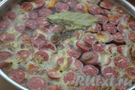 Приправить, посолить по вкусу, добавить лавровый лист. Варить рассольник с колбасой, перловкой и солёными огурцами 7-10 минут на среднем огне. Затем выключить огонь, накрыть кастрюлю крышкой и дать супу настояться минут 10-15.