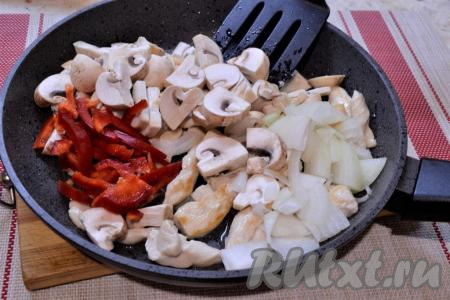 Масло разогреть в сковороде, обжарить куриное филе до лёгкой румяности на среднем огне, периодически перемешивая. Затем добавить в сковороду нарезанные шампиньоны, лук и болгарский перец.