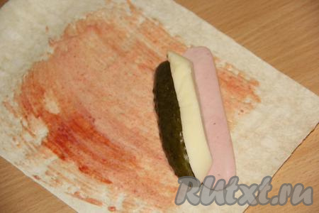 На уголок лаваша выложить брусочки сыра и огурца, половинку сосиски.