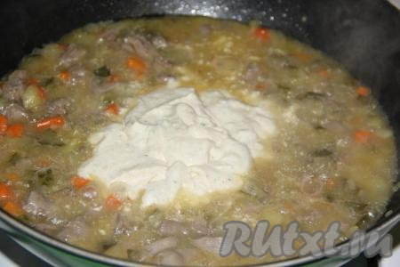 Добавить сметанный соус в сковороду к куриным сердечкам с солёными огурцами.