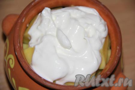 Выложить сметану. Накрыть горшочек с минтаем и картошкой крышкой и поставить в разогретую духовку.