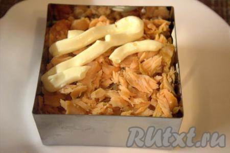 Следующим ровным слоем выложить кусочки очищенной рыбы, утрамбовать и смазать майонезом.