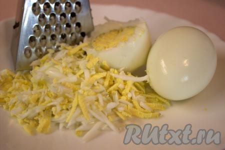 Яйца поместить в кастрюлю, залить водой и отварить вкрутую (с момента закипания воды варить минут 10), затем охладить, очистить и натереть на средней тёрке.