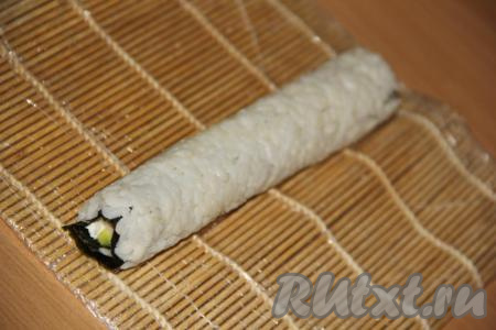 Начиная с края, ближе к которому выложен творожный сыр, свернуть с помощью циновки плотный ролл (слой риса у нас окажется снаружи).