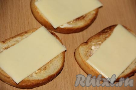 Собрать бутерброды, для этого на каждый обжаренный и остывший кусочек белого хлеба нужно выложить ломтик сыра.