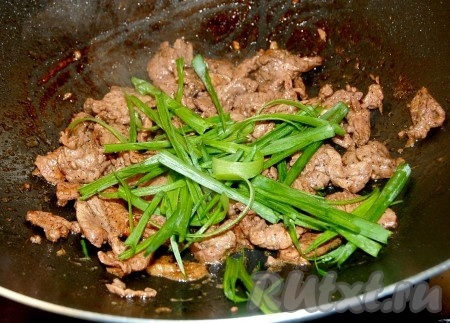 Нарезанный зеленый лук добавить в вок к мясу. 
