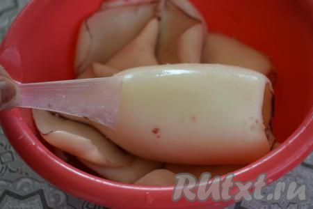 Достаём кальмаров из миски с холодной водой и промываем их, счищая оставшуюся тёмную плёночку и вычищая возможно оставшиеся внутренности. Далее промытых кальмаров нужно ещё очистить от плотной, прозрачной плёнки, которая покрывает сверху всю тушку. Для этого чуть поддеваем ножом плёночку и далее руками отрываем её. Сходит плёнка очень легко, так что очистить кальмаров не составит никакого труда.