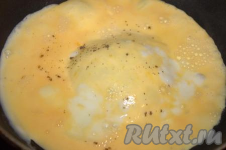 Сковороду смазать растительным маслом, разогреть и влить один половник яичной массы, равномерно распределить, немного посолить и приправить по вкусу специями (я посыпала молотым чёрным перцем). Жарить яичный блинчики с двух сторон на среднем огне до золотистого цвета, затем переложить со сковороды на тарелку. Аналогично приготовить блинчики из оставшегося теста (количество блинчиков зависит от размера сковороды). Яичные блинчики остудить.
