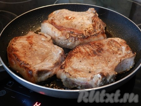 В сковороде разогреть небольшое количество растительного масла и быстро обжарить антрекоты из свинины с обеих сторон до румяной корочки.