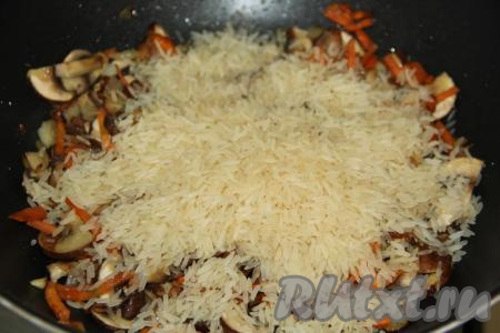 В сковороду с грибами, обжаренными с овощами, всыпать рис.