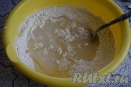 Воду подогреем до температуры 40 градусов и выльем в миску, туда же добавим растительное масло и начнём замешивать тесто вначале ложкой.