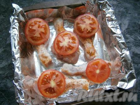 Любую форму для запекания (или противень) застелить фольгой, смазать растительным маслом и выложить голени. На каждой ножке сверху разместить по кружочку свежего помидора.