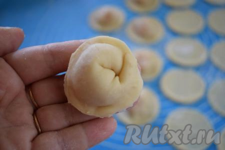 Далее лепим пельмень, скрепляя противоположные края кружочка из теста, а затем соединяем концы получившейся заготовки между собой, как бы скручивая в кружок (как на фото). Таким образом формируем все пельмешки с курицей.