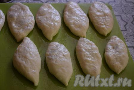 Переворачиваем пирожки с яйцами и зелёным луком швом вниз и выкладываем на досочку, смазанную растительным маслом.