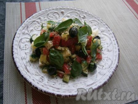 Салат с огурцами, помидорами и моцареллой выложить в салатник (или на плоскую тарелку), посыпать свежемолотым чёрным перцем, орегано и разложить сверху листики зелёного базилика.