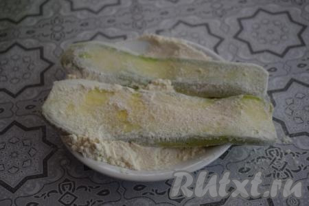 В плоскую тарелку насыпаем муку и обваливаем в ней полоски кабачков с двух сторон.