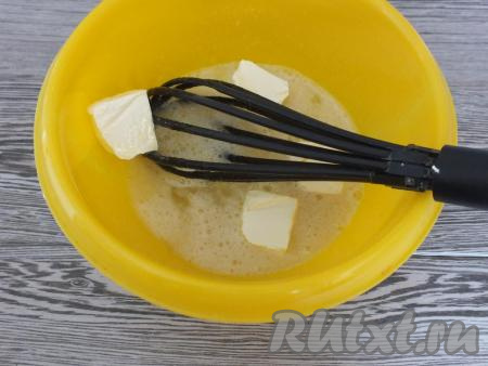 К смеси сахара и яиц добавьте кусочки сливочного масла комнатной температуры, перемешайте венчиком яично-масляную смесь.