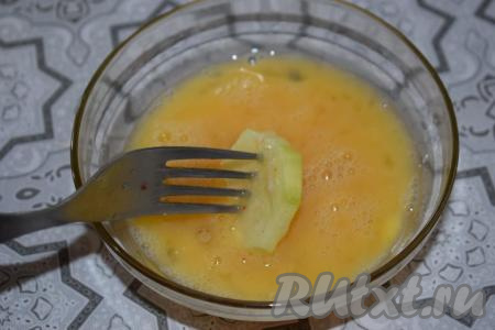 Нарезанные кружочками кабачки сначала полностью окунаем в яйцо при помощи вилки.