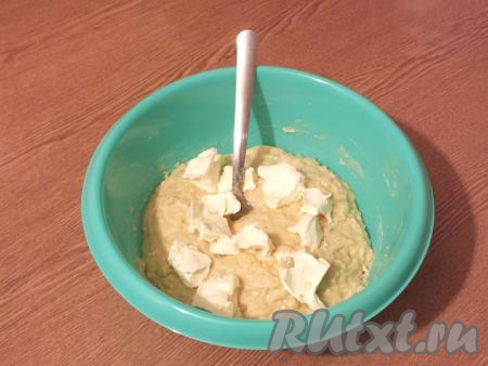 Добавьте в тесто кусочки мягкого сливочного масла (для того чтобы масло стало мягким, его нужно заранее достать из холодильника) и тщательно вмешайте его. Это можно сделать ложкой, миксером с насадками "крюки" или же в хлебопечке. 