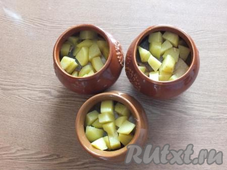 Далее выложите в каждый горшочек ещё по кусочку горбуши и равномерно разложите оставшийся картофель.