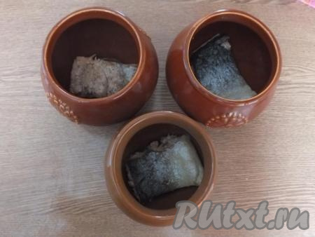 Обжаренную рыбу, по одному кусочку, выложите на дно горшочков.