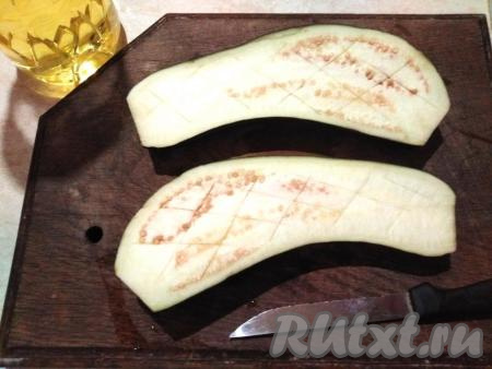 Баклажан разрезаем вдоль пополам, отрезав "кончики" с двух сторон. Затем на мякоти баклажана делаем крестовые глубокие надрезы и смазываем растительным маслом. Важно, чтобы масло попало в надрезы! Подготовленные половинки баклажана срезами вверх выкладываем в форму для запекания и отправляем в духовку, разогретую до 200-220 градусов, на 15 минут.