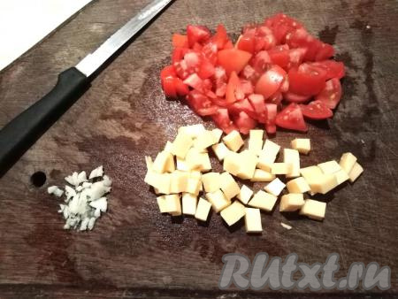 Пока запекаются половинки баклажана, нарезаем кубиками сыр и помидор. Очищаем зубчик чеснока и мелко нарезаем.