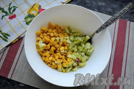 Огурец очистить от кожуры и нарезать мелкими кубиками. Добавить огурец вместе с кукурузой к колбасе и яйцам.