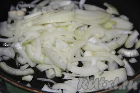 Лук почистить и нарезать тонкими полукольцами. В сковороду влить масло и добавить полукольца лука. 