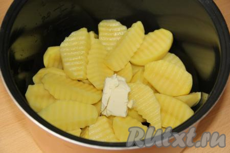 В чашу мультиварки выложить картофель, добавить кусочек сливочного масла.