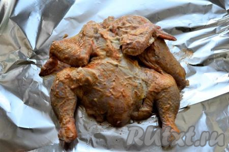Смешать майонез с томатным соусом и приправой для курицы. Цыплёнка посолить и натереть немного чёрным молотым перцем со всех сторон. Затем цыплёнка со всех сторон тщательно смазать соусом из майонеза с томатной пастой, разместить птичку на листе плотной фольги.