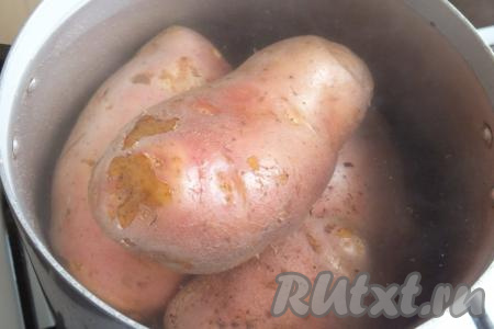 Для начала подготовьте овощи. Вымойте тщательно картофель и, не очищая его от кожуры, поместите в кастрюлю, полностью залейте водой и поставьте вариться до готовности (на это потребуется минут 30 с начала кипения воды - продолжительность варки во многом зависит от сорта и размера клубней).