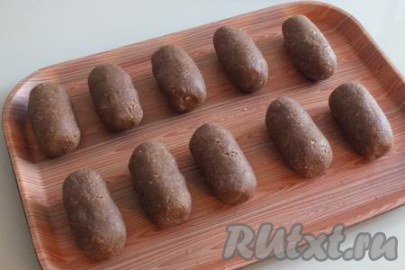 Разделите полученную массу на кусочки весом 70-75 грамм. Сначала скатайте из каждого кусочка теста плотный шарик, потом придайте ему цилиндрическую форму. Выложите пирожные на доску (или поднос) на небольшом расстоянии друг от друга.
