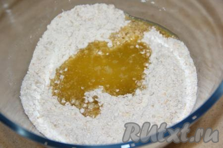 К получившейся сухой смеси добавить растопленное масло с мёдом и горячую воду. 