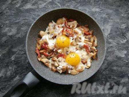 Вбить в сковороду яйца, посолить по вкусу и поперчить, прикрыть сковороду крышкой и на медленном огне выдержать яичницу с шампиньонами и луком 3-4 минуты. 