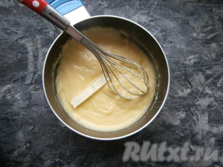 Венчиком перемешать содержимое кастрюли, влить молоко, ещё раз перемешать. Поставить кастрюлю на средний огонь и при постоянном помешивании довести смесь до кипения, а затем проварить до загустения (загустевает крем достаточно быстро - в течение 3-5 минут), снять с огня. В горячий заварной крем добавить кусочек сливочного масла, перемешать. Затем крем накрыть плёнкой встык (плёнка должна лежать на креме) и дать ему полностью остыть, после чего поместить в холодильник на 1-2 часа.