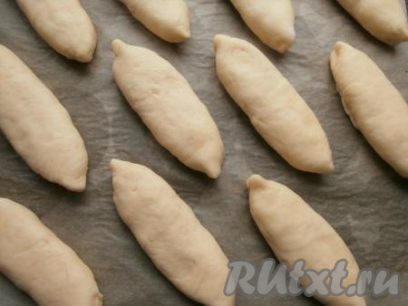 Также сформировать булочки из остального теста, выложить их на достаточном расстоянии друг от друга на противень, застеленный пергаментной бумагой. Прикрыть булочки плёнкой, дать им расстояться минут 20-25 в тепле.