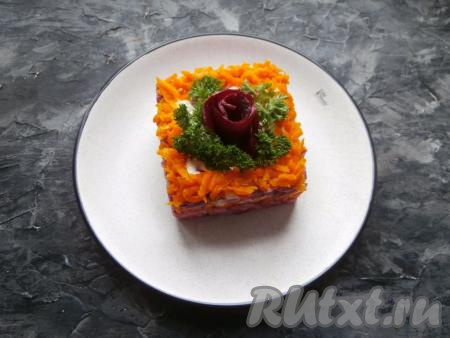 Сверху выложить оставшуюся натёртую морковь (морковку можно выложить ровным слоем или покрыть ею края салата). Украсить салат можно розочкой из свеклы и зеленью.