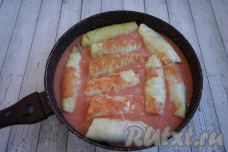 Заливаем наши голубцы получившимся томатно-сметанным соусом, закрываем сковороду крышкой, ставим на огонь, даём закипеть соусу, а затем тушим на небольшом огне 25-30 минут.