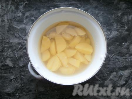 Нарезать картошку крупными дольками (на 4-6 частей), поместить в кастрюлю, полностью залить водой. Кастрюлю поставить на огонь, после закипания всыпать щепотку соли, варить дольки картофеля до полуготовности (10-12 минут).