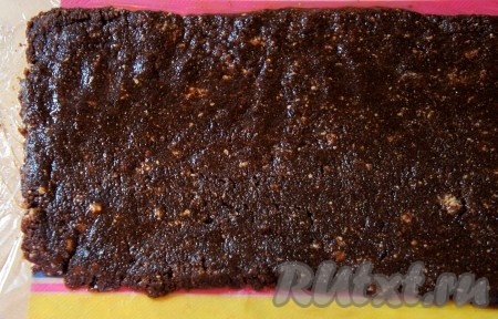Расстелить пищевую плёнку. Шоколадное печенье, смешанное с маслом, равномерно распределить по плёнке, сформировав прямоугольник.
