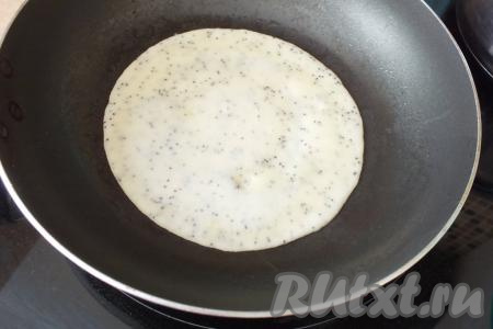 На сковороду налейте 1 столовую ложку растительного масла, разогрейте. Наберите в половник блинное тесто, вылейте в сковороду и распределите его по дну. Жарьте блин на огне чуть меньше среднего, пока верх теста не затянется плёночкой и тесто перестанет быть жидким.