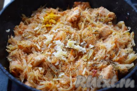 Добавляем к капусте с куриным филе специи по вкусу, выдавливаем очищенные зубчики чеснока через пресс и выключаем огонь.