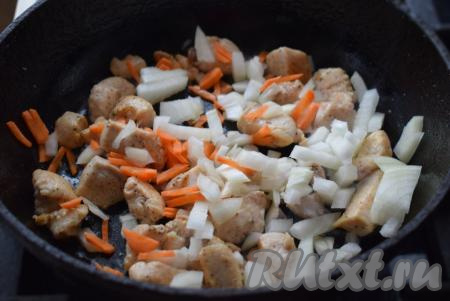 Далее в сковороду к филе кладём лук и морковь, перемешиваем всё и жарим на медленном огне до прозрачности овощей (примерно, 5 минут).